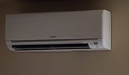 A wall-mounted ductless indoor head set below the ceiling line.